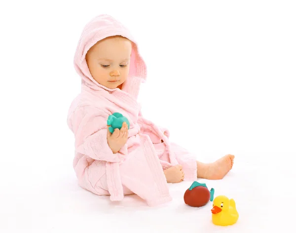 Cute baby in bathrobe playing with water rubber toys — Stock Photo, Image