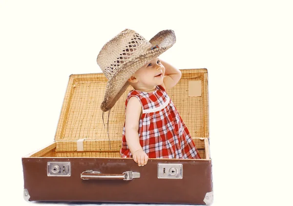 Szczęśliwy uśmiechający się dziecko w kapelusz słoma siedzi na walizka play — Zdjęcie stockowe