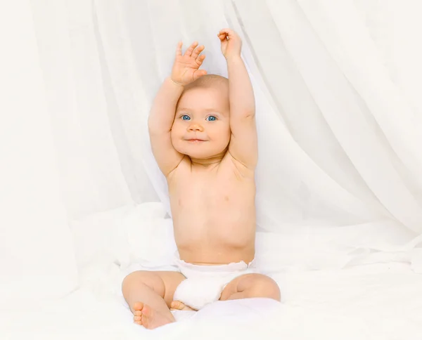 Porträt eines glücklichen aktiven Babys in Windeln, das nachts auf dem Bett spielt — Stockfoto