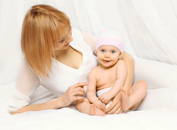 Porträt einer glücklichen Mutter mit Baby, das zusammen auf dem Bett liegt — Stockfoto