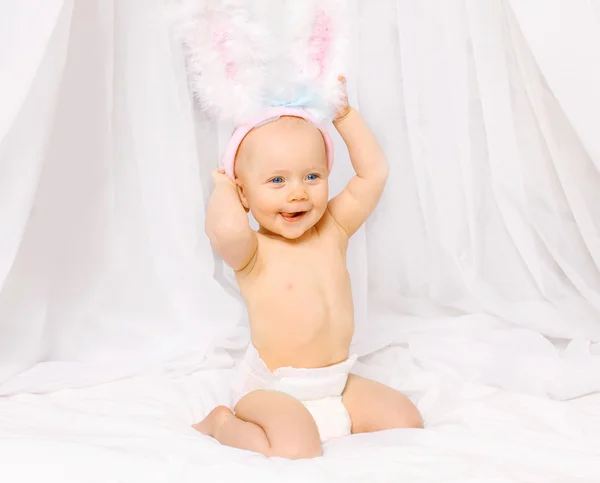Retrato de bebé sonriente positivo en orejas de conejo de Pascua y cinta Imagen De Stock