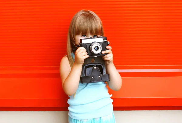 Little smiling girl child with old retro vintage camera against — Stockfoto