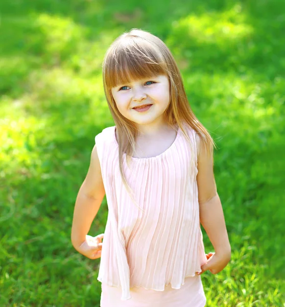 Portrait of cute child little girl on the grass in summer day