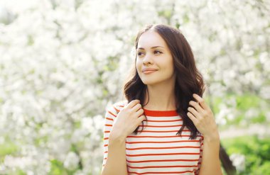 Portrait of happy beautiful young woman in flowering spring gard