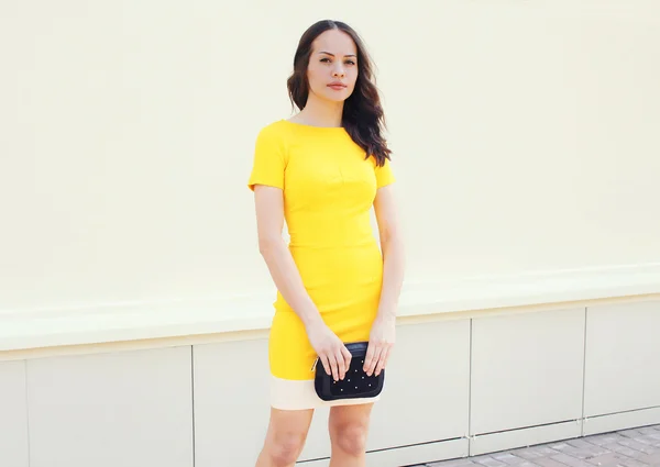 Hermosa mujer joven en vestido amarillo con el bolso negro embrague —  Fotos de Stock