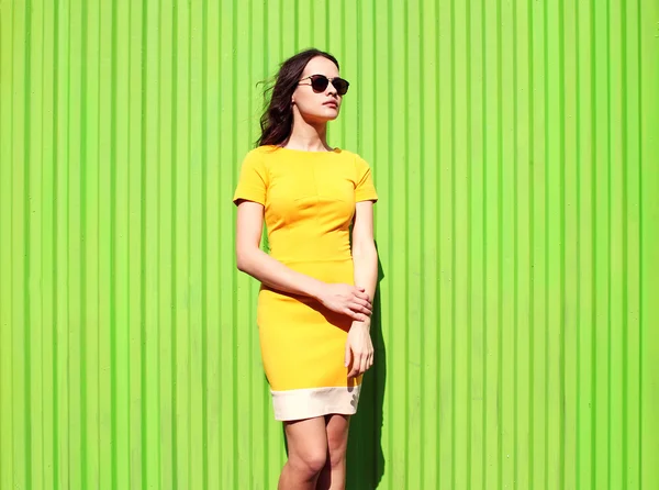 Fashion beautiful young woman in yellow dress and sunglasses aga