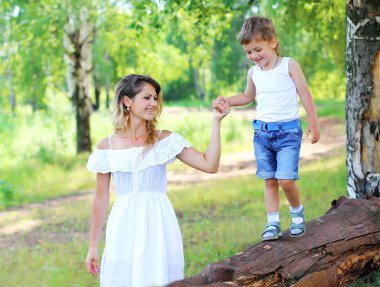 Happy mother walking with child son together outdoors in summer 