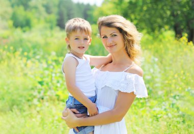 Portrait of happy mother hugging child son outdoors in summer da