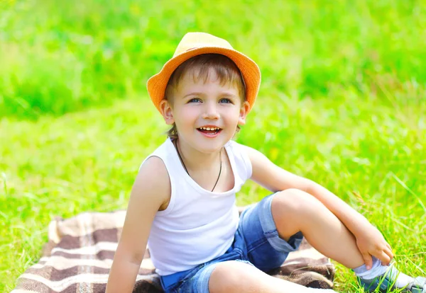Portrait little boy child in hat sitting on the grass in summer — Stok fotoğraf