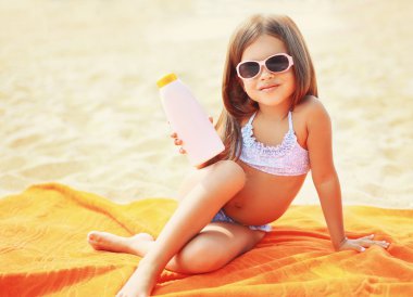 Child sitting on the beach and showing sunscreen skin