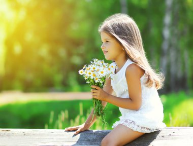 Portrait of cute little girl with bouquet of chamomiles flowers 