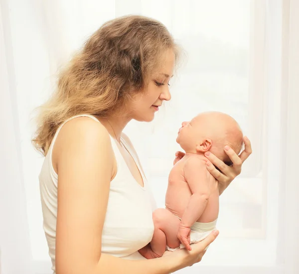 Jovem mãe amorosa segurando as mãos dormindo bebê em casa — Fotografia de Stock