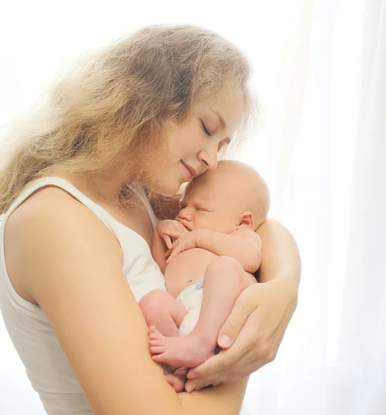 Jovem mãe amorosa ternamente segura as mãos dormindo bebê em h — Fotografia de Stock