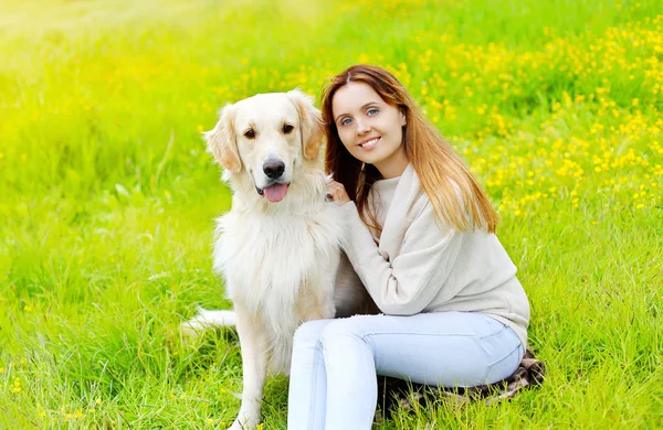 Happy owner and Golden Retriever dog sitting together on the gra — Stock Photo, Image