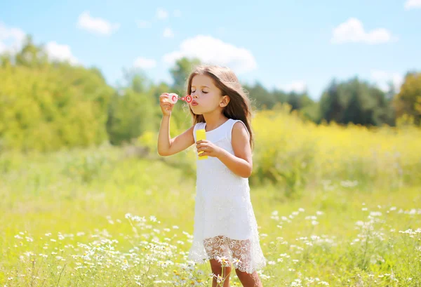 Barn blåsa såpbubblor på ängen i solig sommardag — Stockfoto