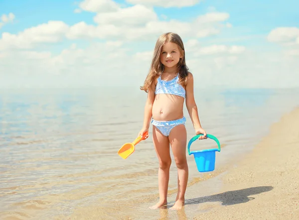 Little girl child with toys playing and having fun on the beach — Stok fotoğraf