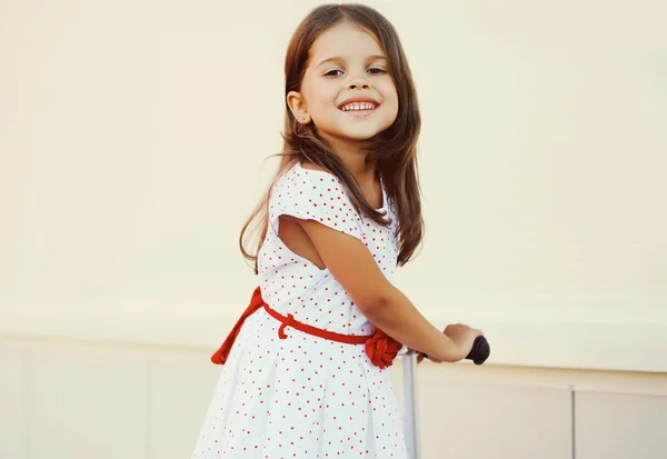 Portrait of smiling little girl on the scooter having fun outdoo — Stockfoto