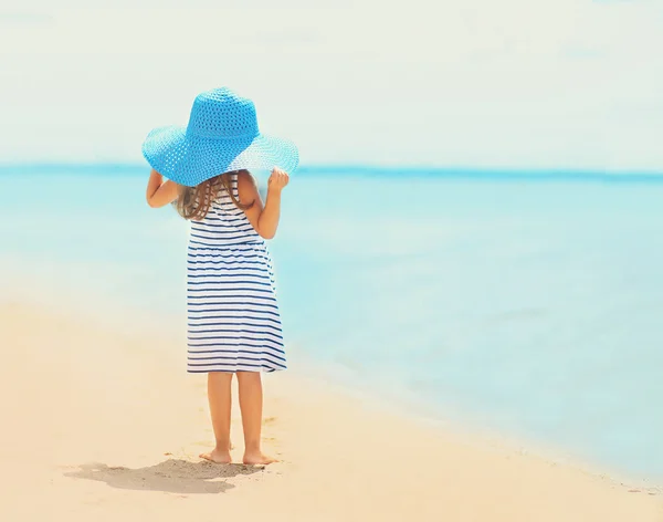 Linda niña en vestido y sombrero de paja disfrutando en la playa —  Fotos de Stock