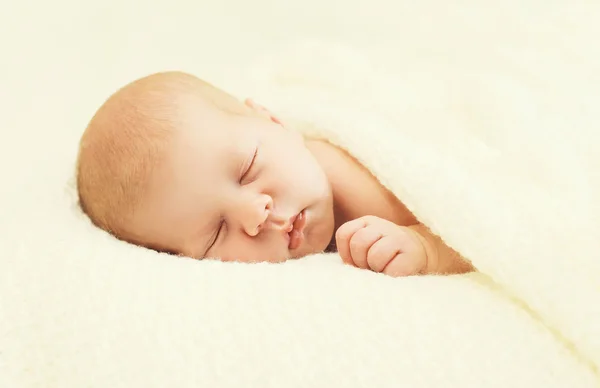 Sweet sleep baby lying under blanket on the bed at home — 图库照片