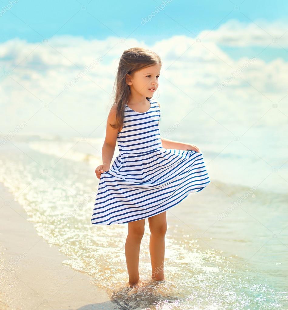 Portrait of beautiful little girl child in a striped dress walki