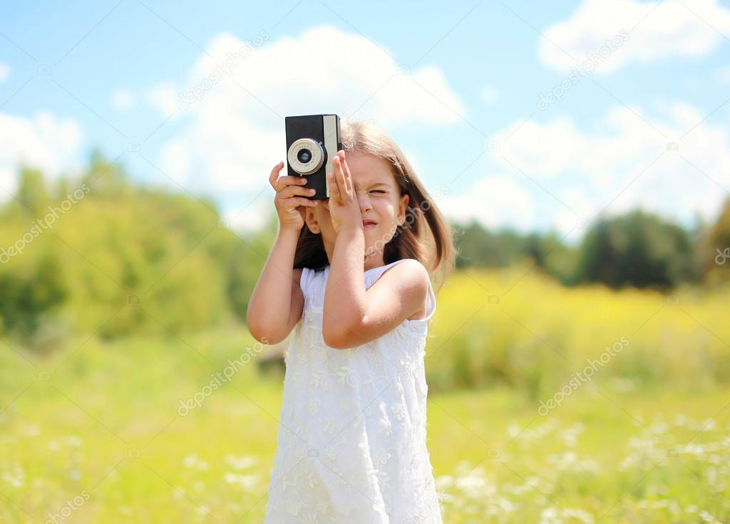 Portrait of little girl child with retro vintage camera outdoors