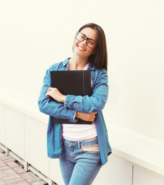 Portrait of happy smiling student girl in glasses with folder ou