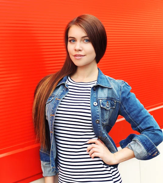 Portrait of beautiful young woman in jeans jacket against the re — Stock Photo, Image