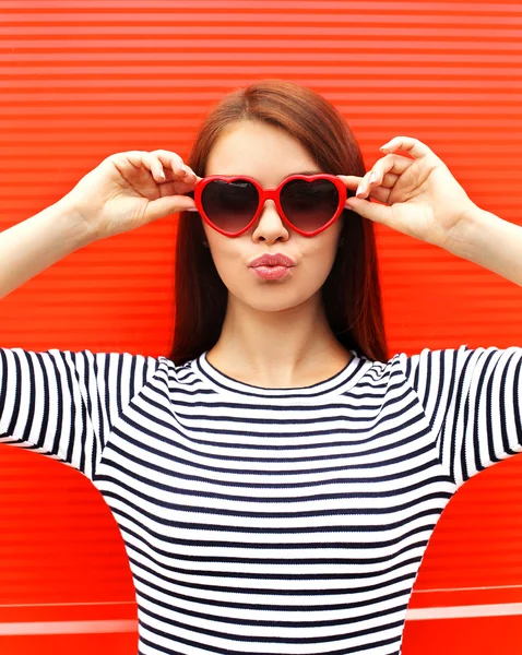 Portrait of pretty young woman in red sunglasses blowing lips ha — Stockfoto