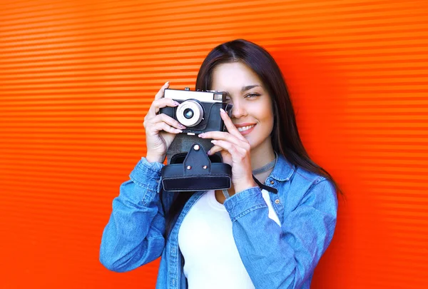 Portrait of pretty woman with retro old vintage camera over red — Stock fotografie