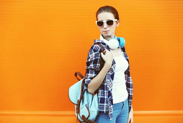 Portrait de jeune femme en lunettes de soleil avec écouteurs et backpa — Photo