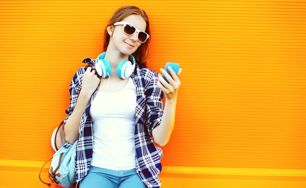Bella ragazza in occhiali da sole e cuffie utilizzando smartphone torna — Foto Stock