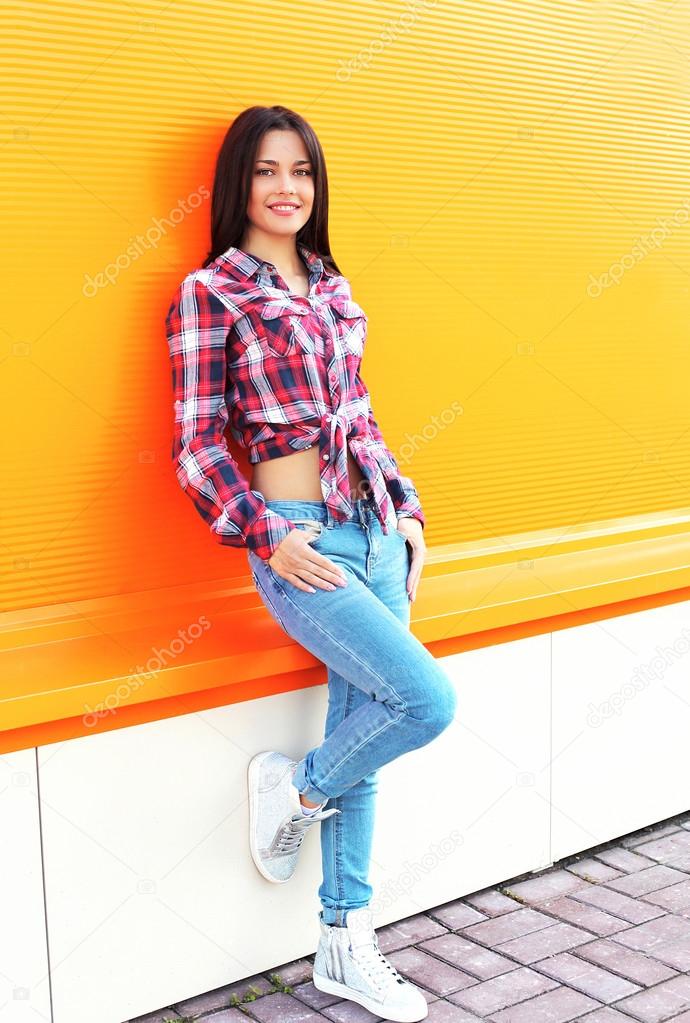 Pretty young smiling woman wearing a checkered shirt and jeans p