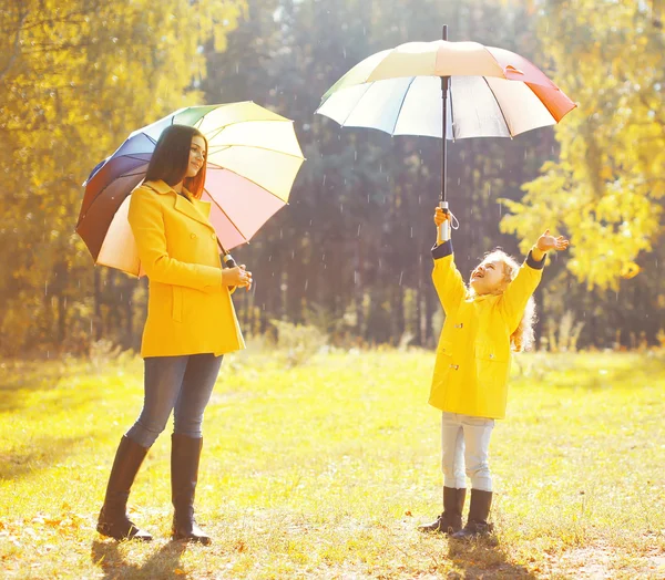 Happy family with umbrellas in sunny autumn rainy day, mother an — Stock Photo, Image