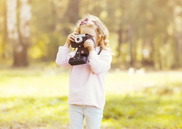 Маленький ребенок со старой ретро камерой делает фото на открытом воздухе — стоковое фото