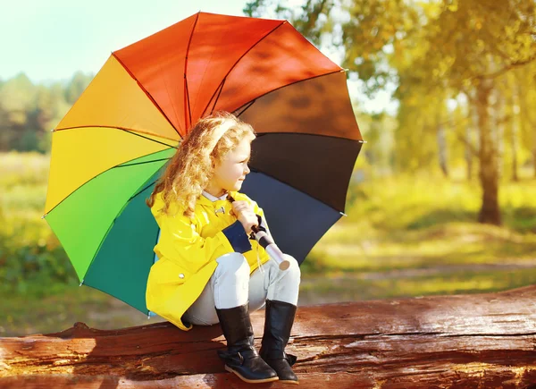 Niña pequeña con paraguas colorido descansando en el parque de otoño —  Fotos de Stock