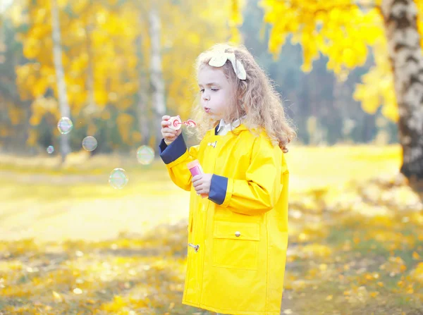 Little girl child blowing soap bubbles in sunny autumn park — Stock Photo, Image