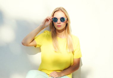 Dikey moda model kadın güneş gözlüğü ve sarı tişört ou