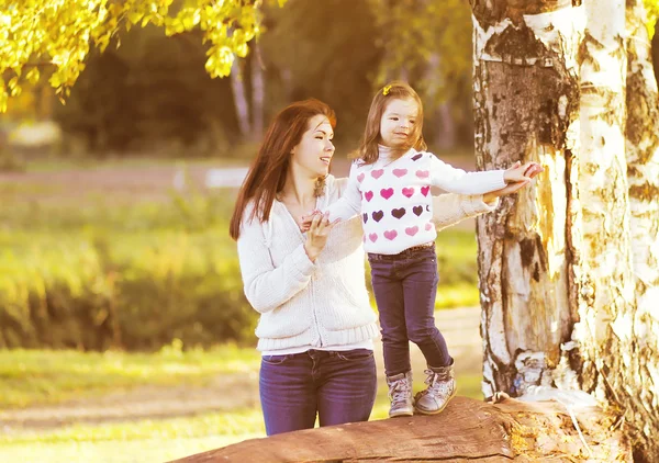 Happy mother and daughter child walking in sunny autumn park — Stock Photo, Image