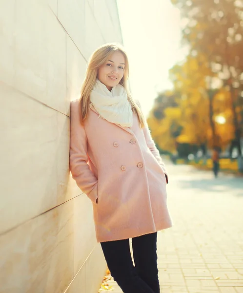 Красива молода усміхнена жінка в рожевому пальто в сонячному автоматі — стокове фото