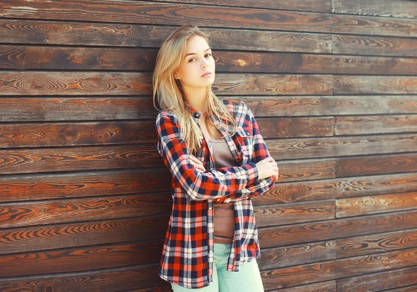 Moda jovem mulher loira em camisa quadriculada sobre marrom de madeira — Fotografia de Stock
