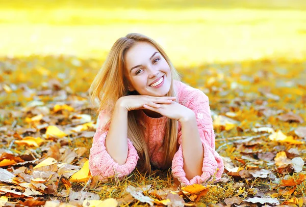 Portrait pretty smiling woman resting lying on leaves in autumn — Stock Photo, Image