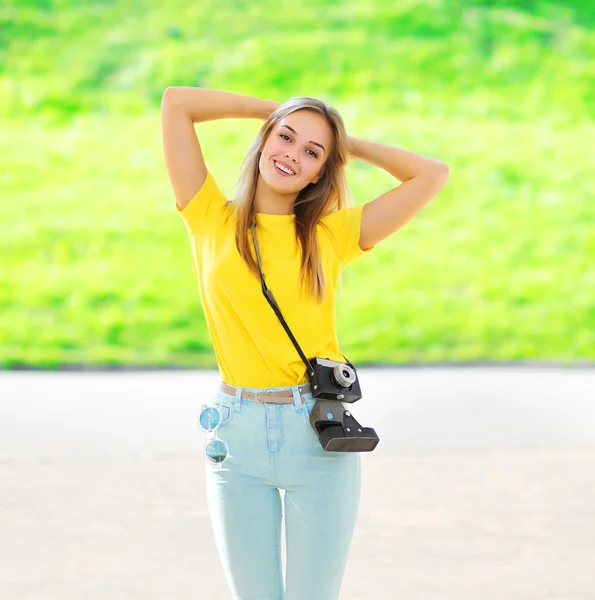 Pretty smiling woman wearing a sunglasses with retro camera posi — Stock Photo, Image