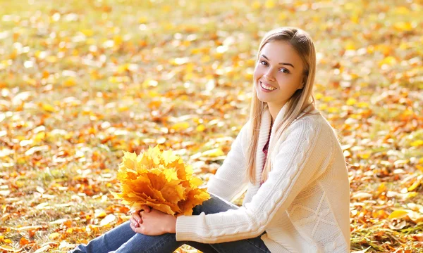 Mulher muito sorridente com folhas de bordo amarelo no sol par outono — Fotografia de Stock