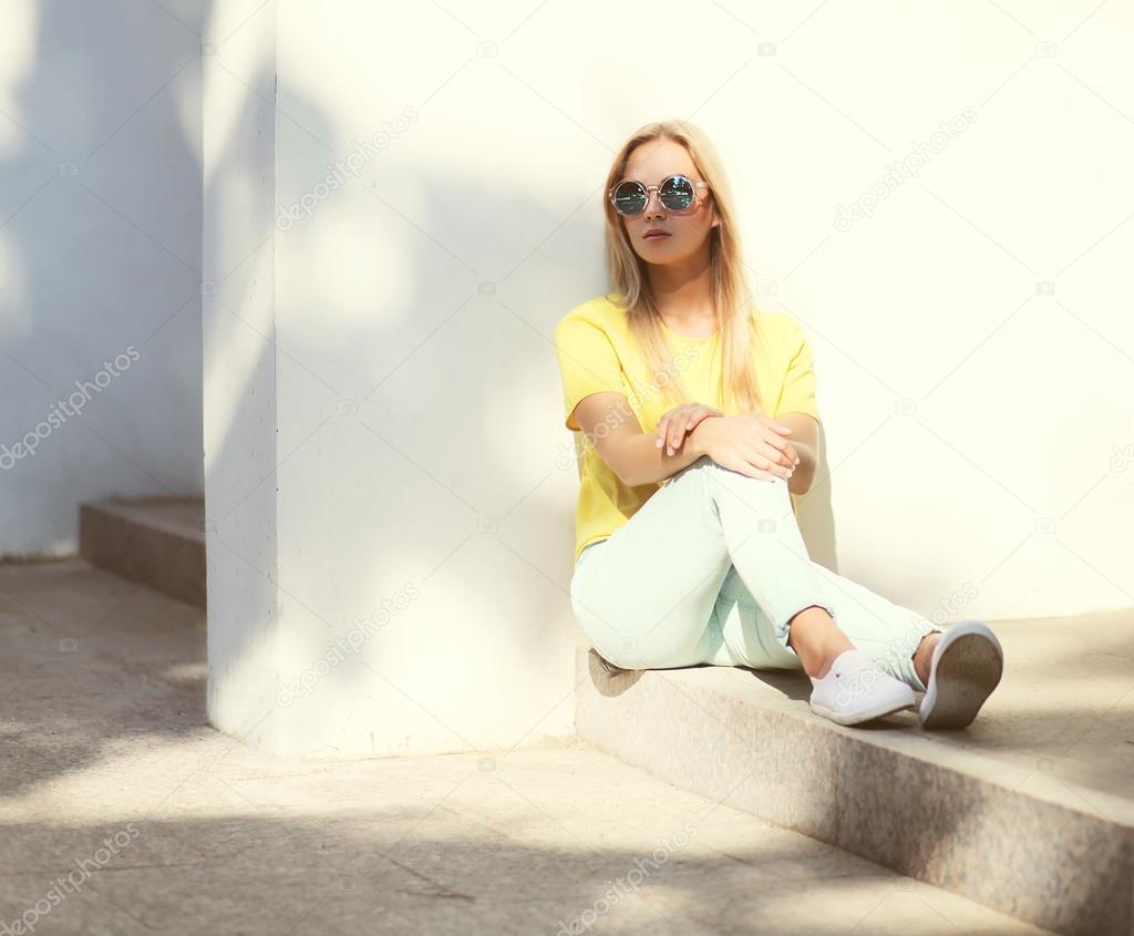 Fashion model woman wearing a sunglasses and yellow t-shirt sitt