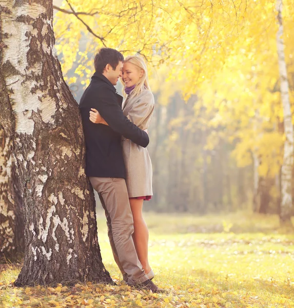 Heureux jeune couple aimant étreignant près de l'arbre dans le parc d'automne — Photo