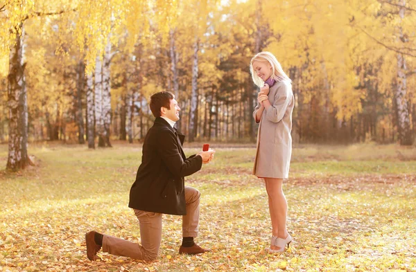 Hombre arrodillado proponiendo anillo a una mujer en el parque de otoño — Foto de Stock