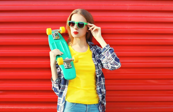 Модная симпатичная девушка в солнцезащитных очках со скейтбордом — стоковое фото
