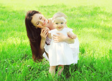 Genç anne ve bebek yaz günde çimenlerin üzerinde yürüyüş