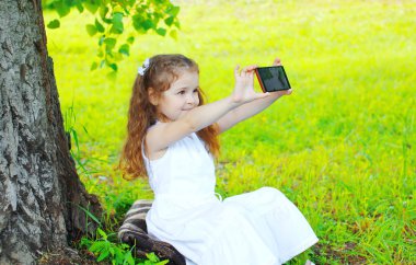 Güzel küçük bir kız çocuk kendi kendine portre Smartphone'da yapma ben