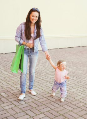 Mutlu anne ve bebek ile alışveriş torbaları şehirde yürüyüş
